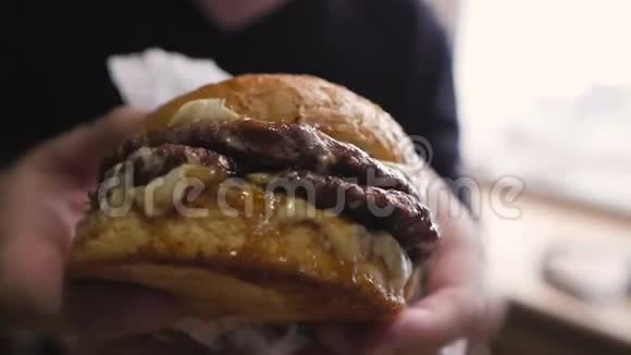 一个男人的特写手里握着一个令人垂涎欲滴的多汁汉堡视频的预览图