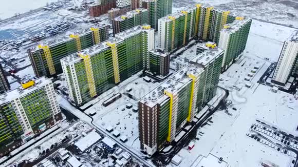 冬季日落时在雪域背景下俯瞰城市动作鸟瞰绿色和黄色的高大视频的预览图