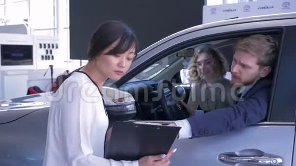 汽车经销商肖像亚洲妇女咨询客户年轻配偶坐在汽车沙龙时购买家庭汽车视频的预览图