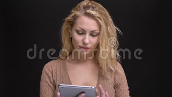 一幅美丽的白种人长发女子的肖像微笑着将绿色的平板电脑屏幕显示在黑色相机上视频的预览图