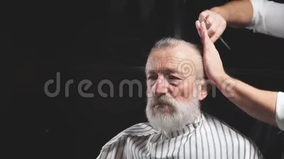 在理发店为一位英俊的老人做美发师的工作视频的预览图