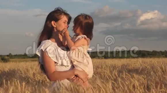 母亲带着婴儿在田里散步手里拿着小麦的小穗小女儿在麦田里吻妈妈视频的预览图