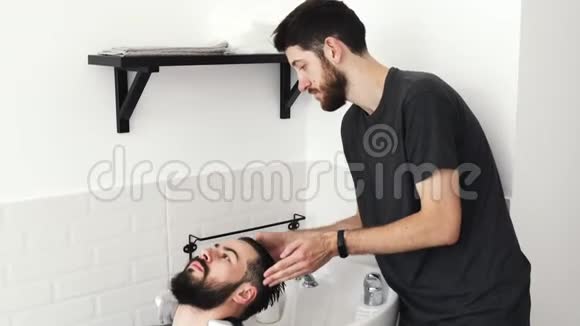 理发师在理发店的水槽里客户的头发视频的预览图