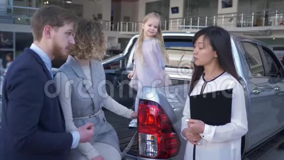 家庭购车职业女经理告知客户年轻夫妇和女孩子在汽车后备箱视频的预览图