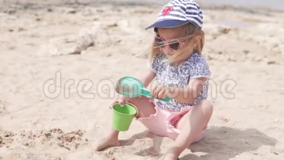 一个金发小孩正在沙滩上玩沙子视频的预览图
