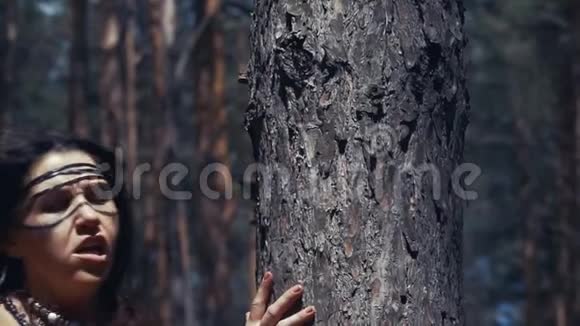 一个穿着皮革和毛皮衣服的深色女人在树林里的慢镜头视频的预览图