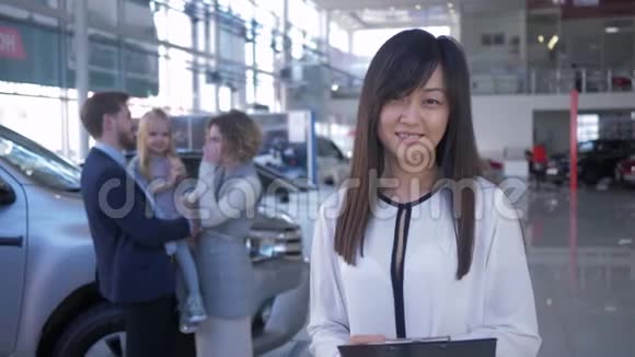 汽车经销商微笑女售货员在背景幸福客户家庭与女儿购买视频的预览图