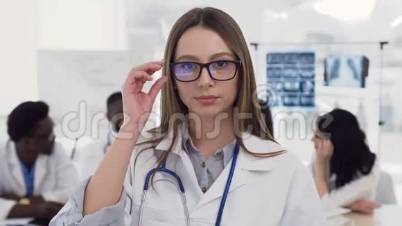 自信的女医生戴着眼镜穿着白色外套脖子上戴着听诊器对着镜头微笑的画像视频的预览图