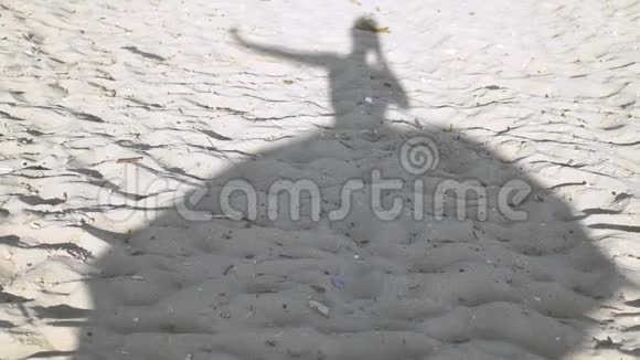 一个穿着裙子在风中飘动的跳舞女孩的沙滩上的剪影视频的预览图