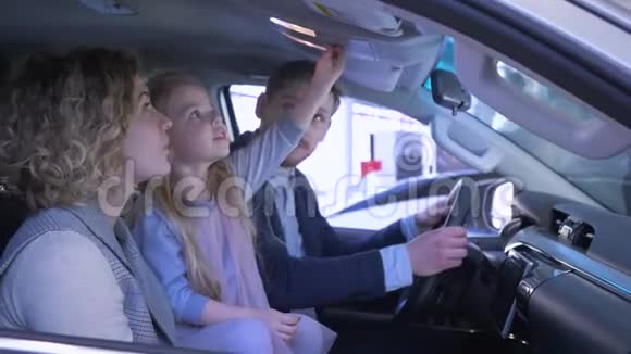 汽车沙龙快乐的妈妈和爸爸和小女孩回顾家庭汽车同时给予积极的手指手势视频的预览图