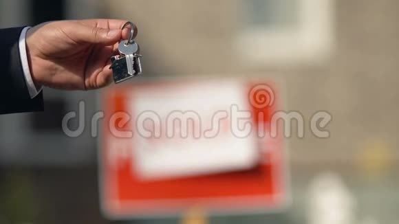 男性手拿公寓钥匙从经纪人出售的标志背景代理客户视频的预览图
