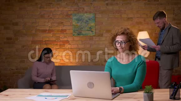 成年女商人使用笔记本电脑的特写镜头兴奋不已与两位女同事在室内庆祝视频的预览图