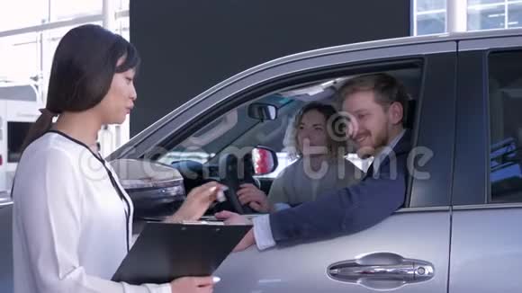 职业经理人亚洲女性告诉买家年轻的家庭坐在汽车沙龙购买汽车视频的预览图