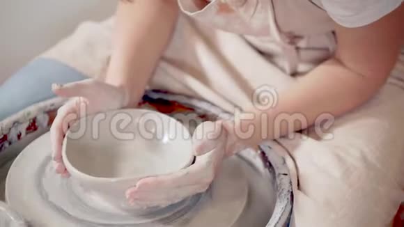 女陶工在工作室里用陶工轮子拉伸粘土做碗视频的预览图