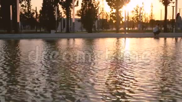 夏天或秋天城市公园湖边的日落背景是杨树和不知名的人行走视频的预览图