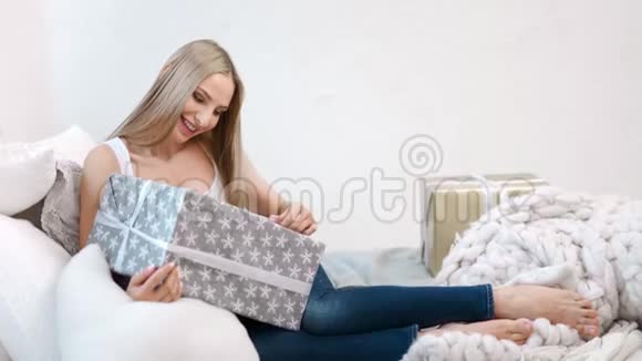 美丽的微笑女人手里拿着大礼盒躺在舒适的沙发上全副武装视频的预览图