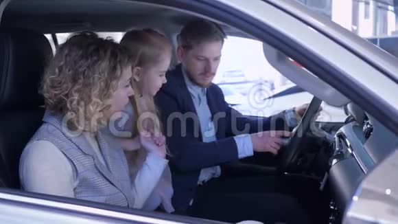 家庭在汽车经销商幸福的夫妻和孩子考虑新汽车而坐在机舱在汽车视频的预览图