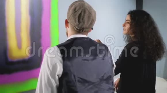 2现代美术馆的两位参观者坐在抽象画前的长凳上视频的预览图
