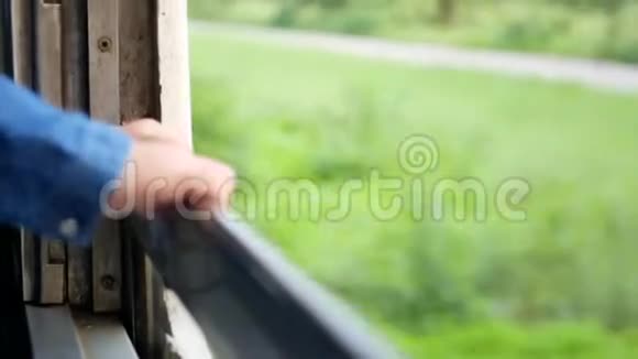 旧的移动的火车窗口有着小婴儿的散焦手和火车外景色的绿色植物视频的预览图