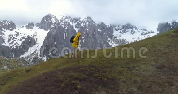 徒步旅行者在白雪皑皑的群山背景下登上一座小山视频的预览图
