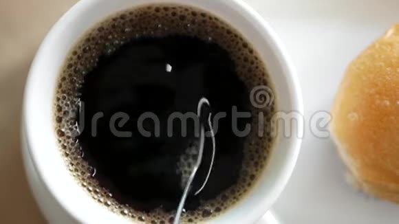 咖啡杯中的热黑咖啡被旁边的面包搅拌视频的预览图