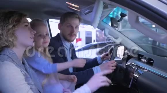 在车展上的家人幸运的父母带着孩子选择了汽车坐在汽车销售的小屋里竖起大拇指视频的预览图