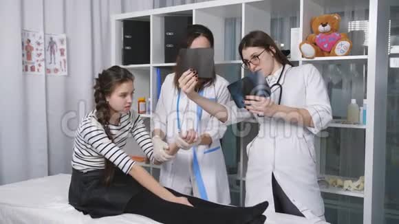 女青年在医生创伤学办公室医生看着这个小女孩病人的双手x光视频的预览图