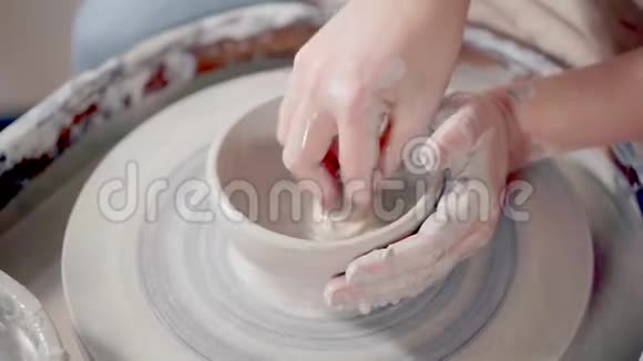 女人在陶工的陶轮上润湿和软化粘土特写视频的预览图