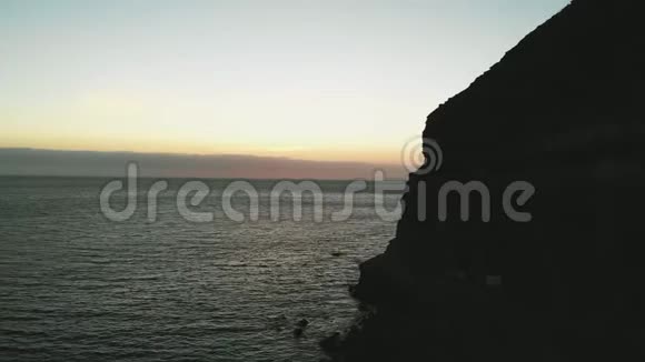 从大西洋上的一个岛屿上日落时的悬崖上的鸟瞰图从一架无人驾驶飞机在加那利加那利岛上拍摄视频的预览图