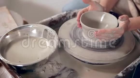陶工车轮上生产陶土碗的女性手的特写镜头视频的预览图