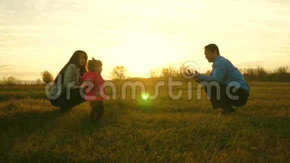 幸福的家庭母女在草坪上玩耍爸爸妈妈和孩子在日落时在草地上玩家庭幸福视频的预览图