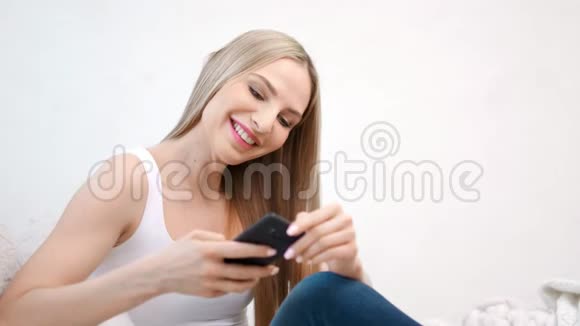 热情的微笑女性在白色工作室背景下在使用智能手机聊天时玩得很开心视频的预览图