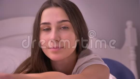 特写照片上年轻迷人的白种人女性若有所思地看着镜头微笑地躺在床上视频的预览图