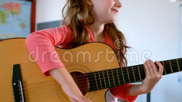 白人中学女生坐在桌子上在教室里弹吉他视频的预览图