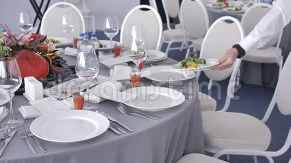 饮食服务服务员在婚礼或研讨会上把盘子和盘子放在客人的桌子上自助餐厅视频的预览图