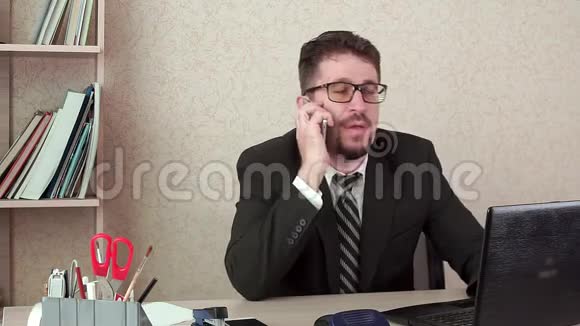 办公室经理带着胡子和眼镜的男人在智能手机上愉快地交谈视频的预览图