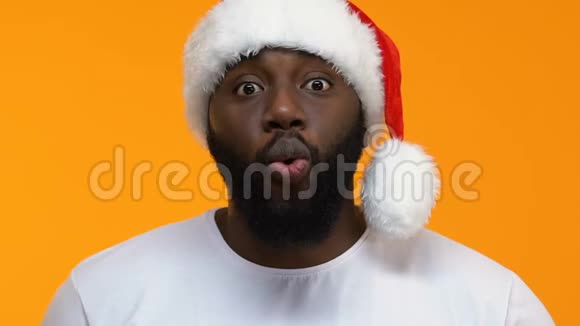 一个戴着黄色背景圣诞帽的美国黑人惊讶地宣布视频的预览图