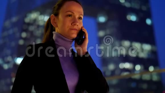 女商人用手机对着现代摩天大楼说话视频的预览图