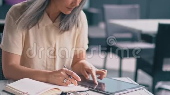 中饱眼福的亚洲女人坐在咖啡馆里工作在餐桌上视频的预览图