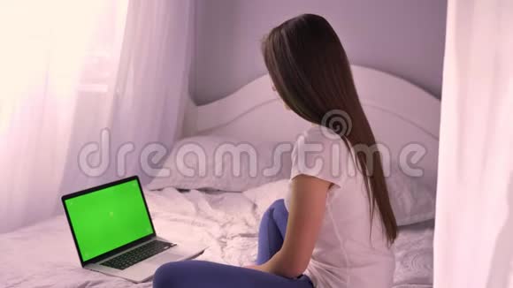 年轻有魅力的高加索女性的特写肖像看着笔记本电脑的绿色克罗玛键屏幕转向视频的预览图