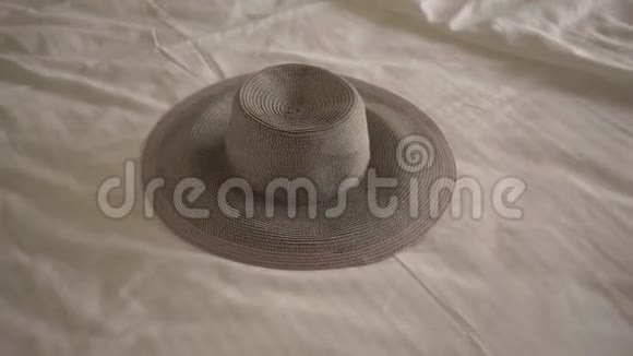 这顶帽子躺在旅馆房间的床上在一张舒适的床上睡在背景中的不知名的女人旅游视频的预览图