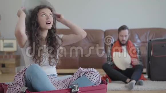 肖像快乐的男人和女人坐在地板上在回家前收拾一个手提箱妻子坐在视频的预览图