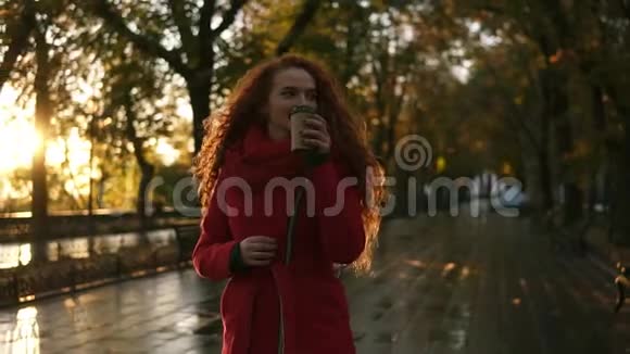 红头发的女人走在城市公园里天气寒冷她穿着红色的外套和针织围巾长发视频的预览图