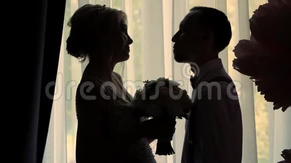 窗户对面新娘和新郎的黑暗轮廓女孩和年轻人站在一边面对着每一个人视频的预览图