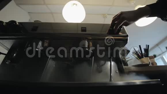 一只女性手转动一台专业的咖啡机蒸汽从里面流出这是一个很近的底景视频的预览图