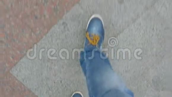 穿着牛仔裤和鞋子的男人沿着街道上的近景视频的预览图
