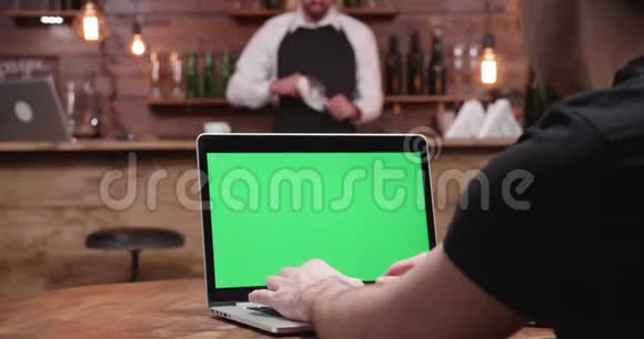 手提电脑在绿色屏幕的现代笔记本电脑上快速打字视频的预览图