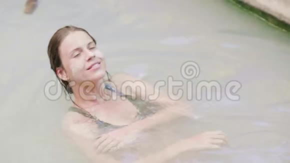 美丽的女人在户外水疗中心的天然泉水中的矿物浴中游泳年轻女子正在享受热浴视频的预览图