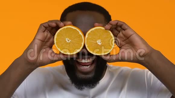 嬉戏的非洲男性眼睛前拿着橙色切片维生素营养健康视频的预览图