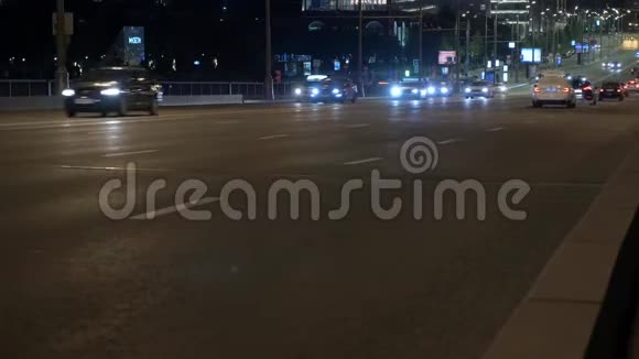 在夜间城市的街道上开着亮灯的汽车视频的预览图